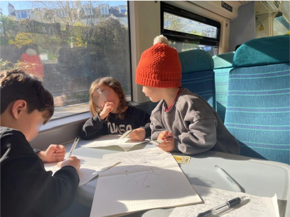 Maurice's children on the train, with pens and paper