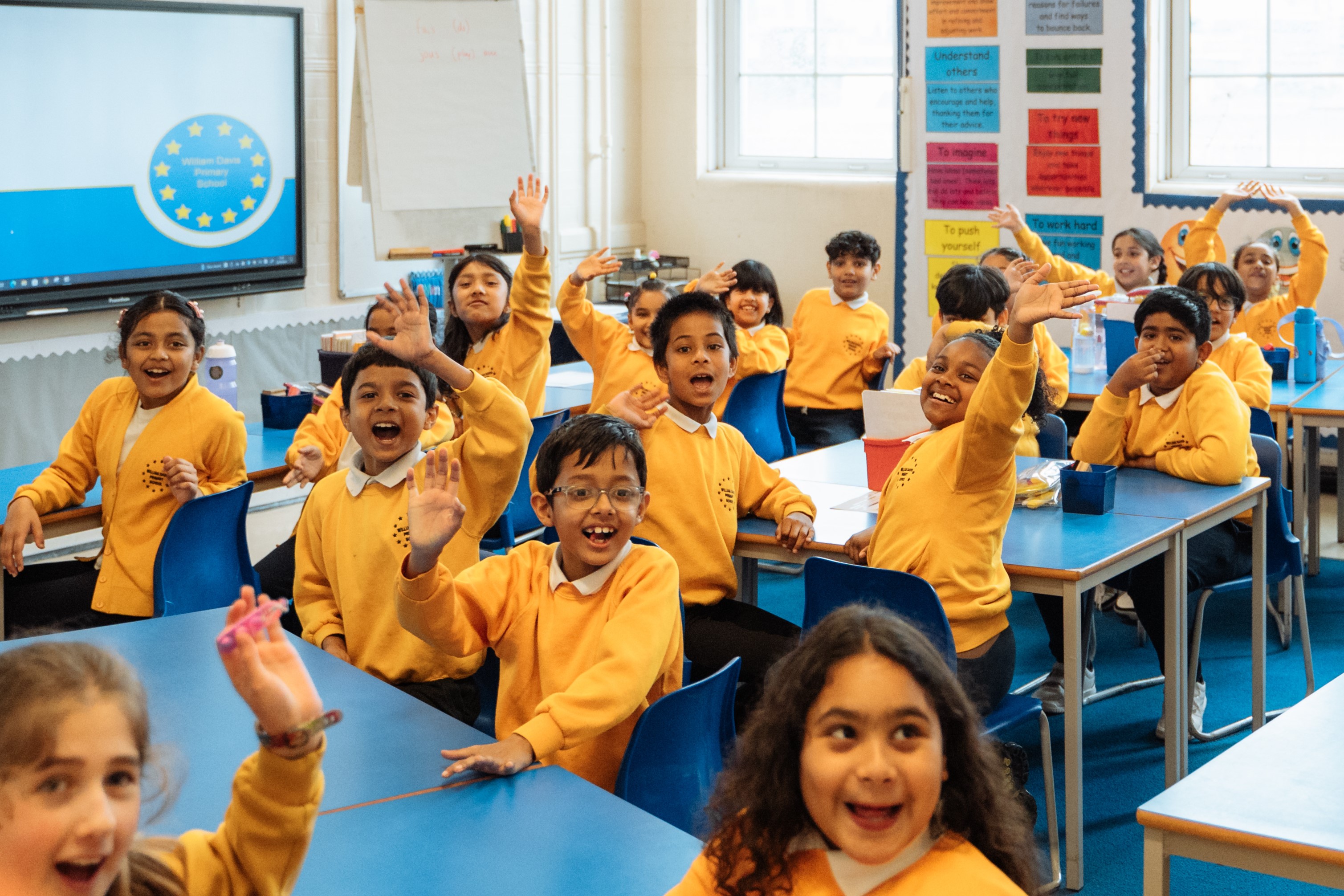 Children raising hands in class