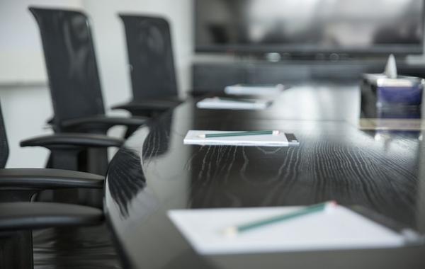 Photo of chairs around a table, with paper on the table, ready for a meeting