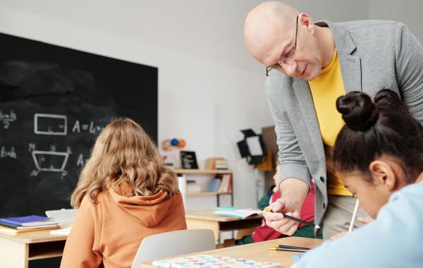 Teacher helps children in a classroom