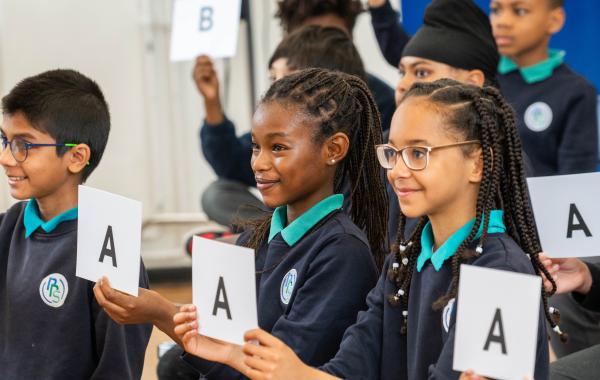 Children holding up cards during a live assembly quiz