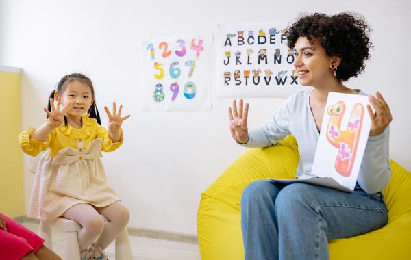 Woman and young girl, holding up four fingers to show the number 4