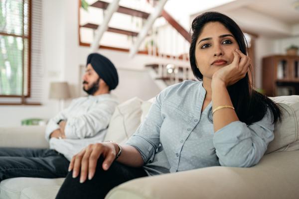 A man and woman sat on a sofa, turned away from each other